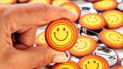 Fingers Holding a 1.5 Inch Round Smiley Face Button