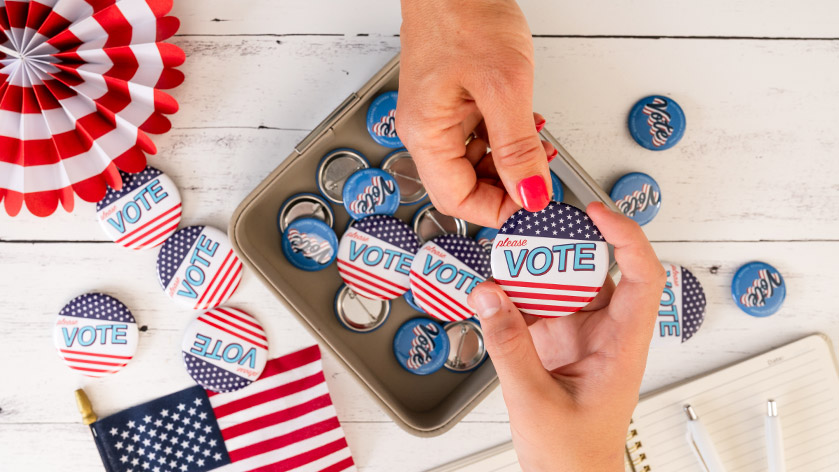 Hands Exchanging "Please Vote" Campaign Buttons of Various Sizes