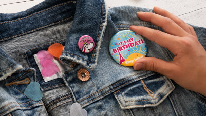 Hand Pinning a Large Birthday Button on a Denim Jacket