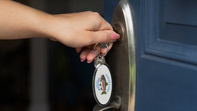 Hand unlocking a door with an oval keychain