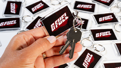 Hand holding a G FUEL rectangle keychain with keys attached