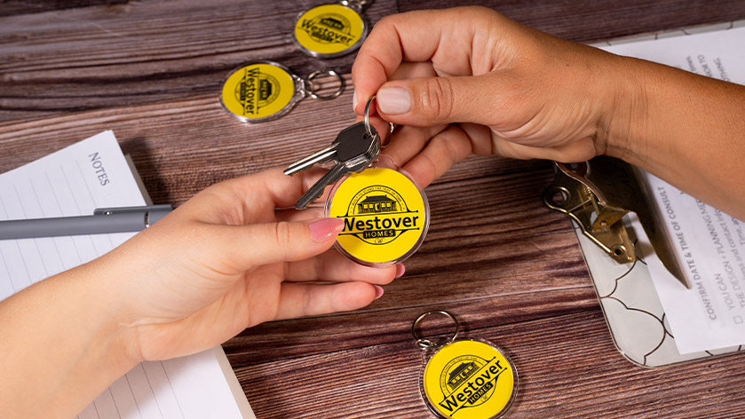 Hands passing a round keychain for Westover Homes