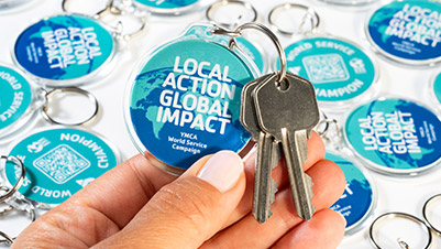 Closeup of a hand holding a round keychain with keys attached for YMCA World Service Campaign