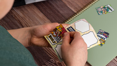 Child Sticking Kiss Cut Stickers to a Notebook