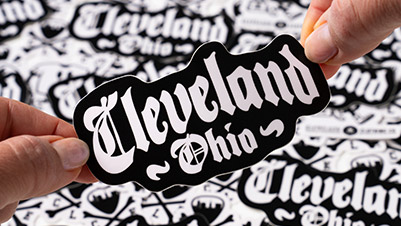 Hands Holding a Die Cut Sticker that Reads Cleveland, Ohio