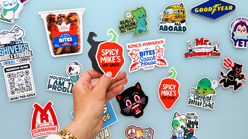 A Variety of Custom Shape Flexible Magnets with a Hand Holding a Pepper Shaped Magnet